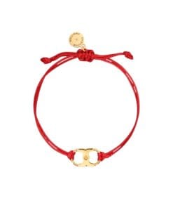 A close-up of the Tory Burch Embrace Ambition Bracelet in Red Gold featuring the 18k-gold plated Gemini Link charm on a red cord.