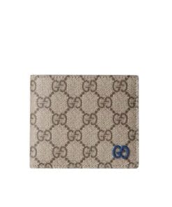 Close-up view of the Gucci GG Supreme bi-fold wallet, showing the beige canvas exterior and the contrasting blue leather interior detail.