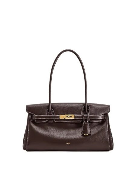 A stylish woman carrying the JW PEI Yara Shoulder Bag in Dark Brown made of vegan leather.